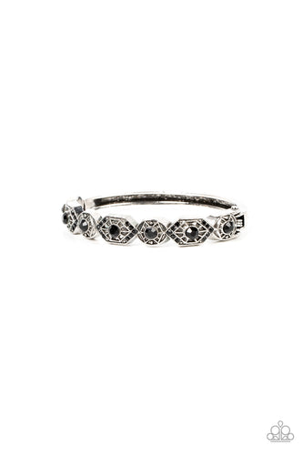 Dotted with dainty black rhinestones, geometrically patterned silver frames alternate across the front of a bangle-like bracelet for an edgy pop of shimmer. Features a hinged closure. 