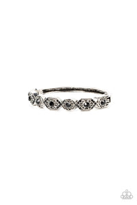 Dotted with dainty black rhinestones, geometrically patterned silver frames alternate across the front of a bangle-like bracelet for an edgy pop of shimmer. Features a hinged closure. 