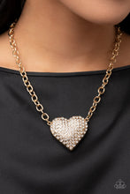 Load image into Gallery viewer, A dramatically oversized gold heart frame is encrusted in row after row of dazzling white rhinestones, resulting in a heart-racing sparkle below the collar. Features an adjustable clasp closure.
