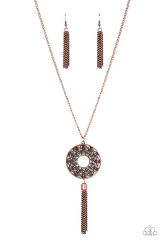 Whirling with a studded mandala-like motif, a rustic copper frame swings from the bottom of an extended copper chain for a dizzying effect. A copper tassel dances from the bottom of the ornate frame, adding a whimsical movement to the seasonal centerpiece. Features an adjustable clasp closure.