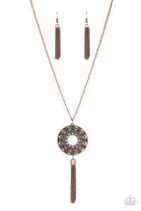Whirling with a studded mandala-like motif, a rustic copper frame swings from the bottom of an extended copper chain for a dizzying effect. A copper tassel dances from the bottom of the ornate frame, adding a whimsical movement to the seasonal centerpiece. Features an adjustable clasp closure.