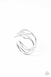 A silver wire heart is encircled in an oversized silver hoop, resulting in a heart-stopping shimmer. Earring attaches to a standard post fitting. Hoop measures approximately 2" in diameter. 