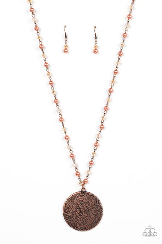 An oversized copper disc stamped in a whimsical floral motif, swings from the bottom of a pearly and crystal-like coppery beaded chain, resulting in a romantic cottagecore inspired pendant. Features an adjustable clasp closure. 
