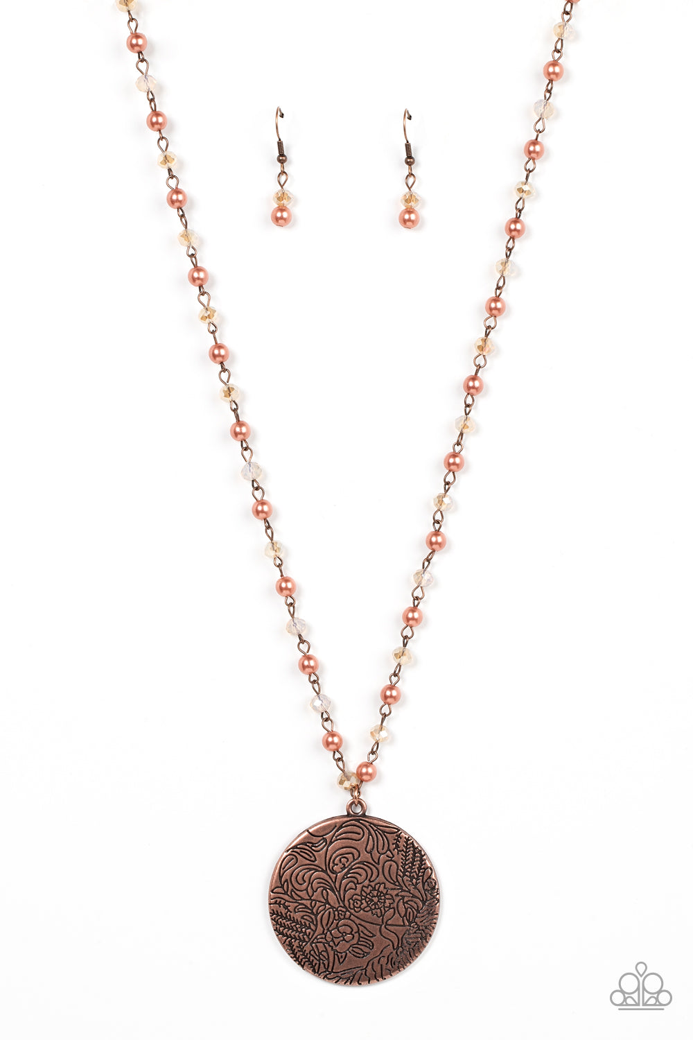 An oversized copper disc stamped in a whimsical floral motif, swings from the bottom of a pearly and crystal-like coppery beaded chain, resulting in a romantic cottagecore inspired pendant. Features an adjustable clasp closure. 