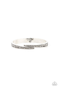 Encrusted in stacked sections of antiqued silver studs and smoky hematite rhinestones, two silver bars delicately overlap at the center of the wrist, resulting in an edgy cuff-like bangle. Features a hinged closure.