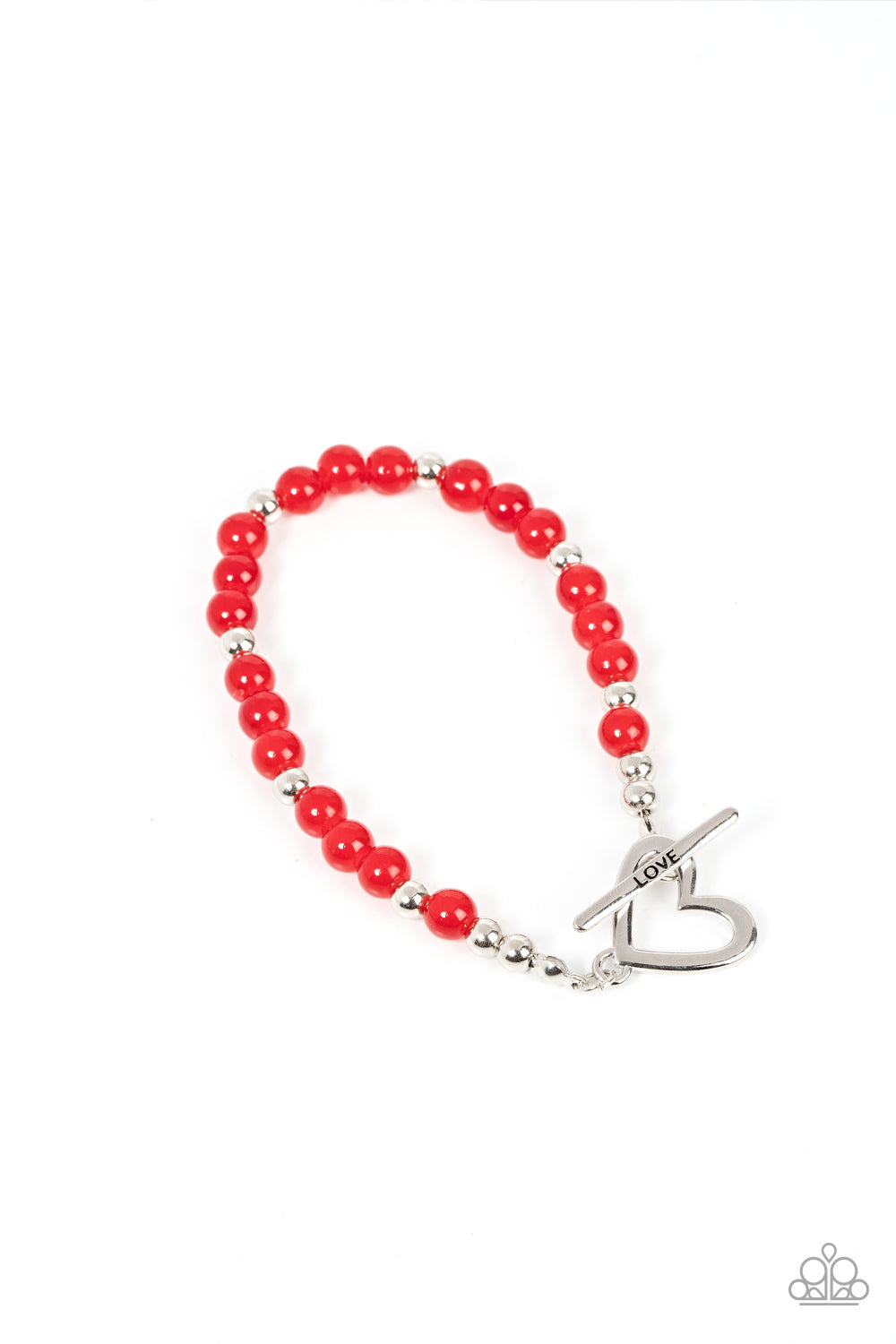 A shiny silver heart frame interlocks with a toggle closure at the center of a shiny silver and glassy red beaded bracelet. The silver toggle is stamped in the word, 