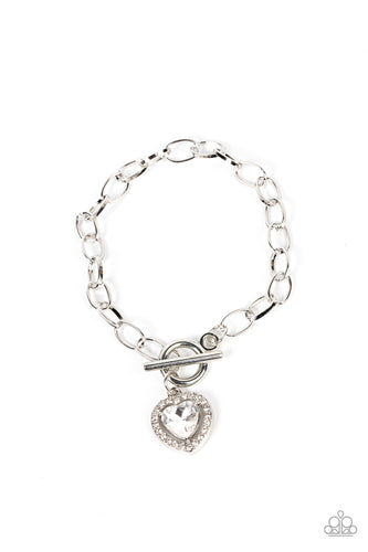 Bordered in glassy white rhinestones, a white heart shaped gem sparkles from a toggle closure at the center of an oval silver linked chain for a flirtatious fashion around the wrist. Features a toggle closure.