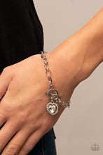 Load image into Gallery viewer, Bordered in glassy white rhinestones, a white heart shaped gem sparkles from a toggle closure at the center of an oval silver linked chain for a flirtatious fashion around the wrist. Features a toggle closure.
