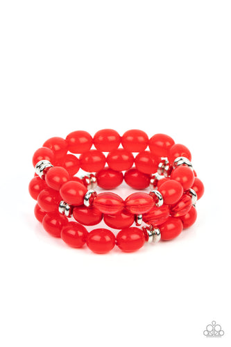 Infused with silver accents, rows of glassy, opaque and acrylic red beads are threaded along stretchy bands around the wrist, resulting in fiery layers.