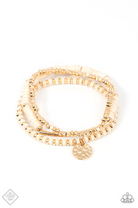 A collection of shiny gold square and oval beads, earthy white stone discs, a hammered gold disc, and a curved gold cylinder, are threaded along stretchy bands, making three distinctive designs that create a trendsetting display as they stack up the wrist. 