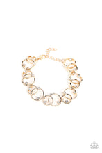 Load image into Gallery viewer, Sporadically dotted in glassy white rhinestones, asymmetrical pairs of overlapping gold rings delicately link around the wrist for a dizzying display of industrial refinement. Features an adjustable clasp closure.
