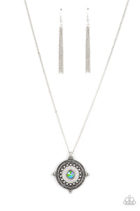 An iridescent green rhinestone is pressed into the studded center of a compass inspired frame, creating a stellar pendant at the bottom of an extended silver chain. Due to its prismatic palette, color may vary. Features an adjustable clasp closure. 