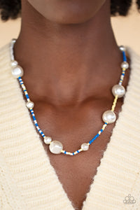 Irregular-shaped pearls in varying sizes are scattered amongst blue, yellow, and white seed beads that are threaded along a wire, resulting in a refreshing and playful style below the collar. 