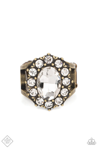 A dauntless oval rhinestone is encircled by dainty sparkling gems. Accented with petite antiqued brass studs, the dramatic design joins with an airy layered brass band to create a captivating arrangement atop the finger. Features a stretchy band for a flexible fit.  Sold as one individual ring.  New Kit Fashion Fix