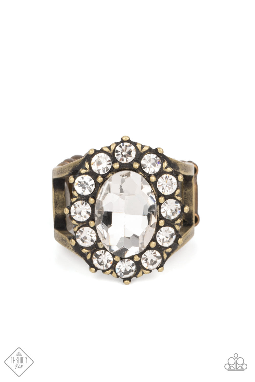 A dauntless oval rhinestone is encircled by dainty sparkling gems. Accented with petite antiqued brass studs, the dramatic design joins with an airy layered brass band to create a captivating arrangement atop the finger. Features a stretchy band for a flexible fit.  Sold as one individual ring.  New Kit Fashion Fix