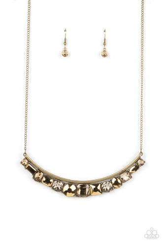 A curved bar of antiqued brass is trimmed with a mashup of glitzy aurum and faceted golden topaz gems that shimmer inside studded brass frames, creating a scintillating sparkle below the collar. Features an adjustable clasp closure. 