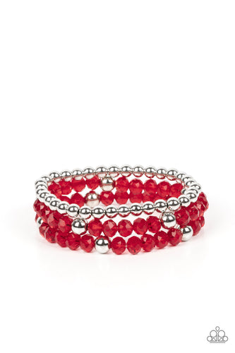 A playful collection of shiny silver beads and sparkly red crystal-like beads are threaded along stretchy bands around the wrist, resulting in colorful layers.