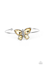 Load image into Gallery viewer, A silver butterfly with yellow teardrop rhinestone wings and a white-rhinestone body delicately perches atop a shiny silver cuff. Featured inside The Preview at GLOW!
