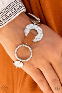 An assortment of silver hoops and discs are hammered in handcrafted texture as they link around the wrist. A strip of brown leather connects two of the pieces, adding a touch of rustic charm to the design. Features an adjustable clasp closure.  Sold as one individual bracelet.  New Kit Fashion Fix