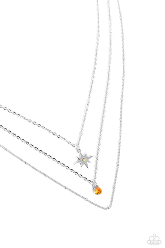 Three mismatched silver chains layer across the chest. Dotted in a dainty iridescent rhinestone, a shiny silver charm swings from the uppermost chain above a solitaire orange rhinestone for a twinkly finish. Features an adjustable clasp closure. 