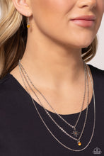 Load image into Gallery viewer, Three mismatched silver chains layer across the chest. Dotted in a dainty iridescent rhinestone, a shiny silver charm swings from the uppermost chain above a solitaire orange rhinestone for a twinkly finish. Features an adjustable clasp closure. 
