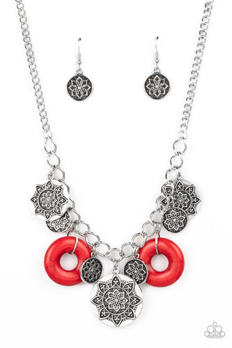  A collection of silver discs, embellished with intricate mandala-like designs, dances along a thick silver chain, with a pair of polished red stone rings adding a pop of color to the rustic design. Features an adjustable clasp closure. 