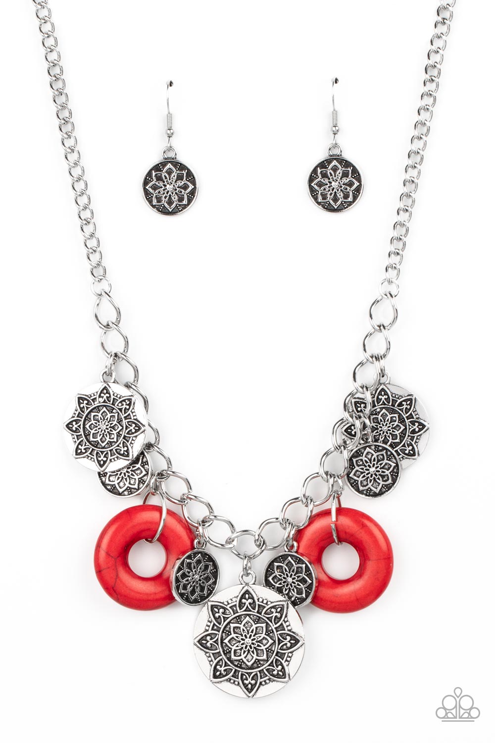  A collection of silver discs, embellished with intricate mandala-like designs, dances along a thick silver chain, with a pair of polished red stone rings adding a pop of color to the rustic design. Features an adjustable clasp closure. 