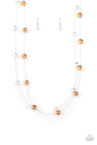 Glassy, orange and iridescent beads sporadically dot two strands of skinny wire, creating the illusion of floating spheres falling down the chest. One side of each marble-like bead is dipped in a silver coating, adding a hint of metallic shimmer to the abstract design. Features an adjustable clasp closure. Due to its prismatic palette, color may vary. 