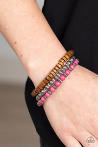 Vivacious pink stone beads, wooden beads, and silver antiqued beads are threaded along elastic stretchy bands. Sprinkled between the colorful beads are dainty silver-studded flower beads for a whimsical finish.