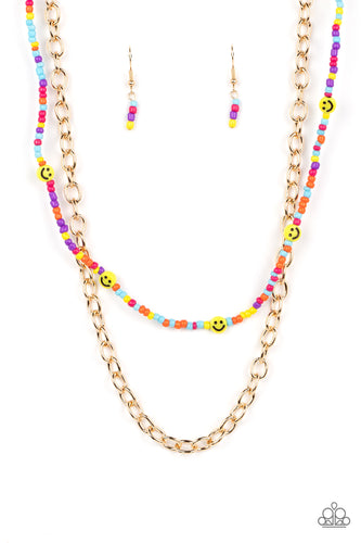 Layered together with a bold gold chain, dainty multicolored seed beads and yellow smiley face beads are threaded along an invisible wire below the collar, resulting in a colorfully retro design. Features an adjustable clasp closure. 