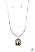 Load image into Gallery viewer, An oversized, topaz, emerald-cut gem is bordered by tiny white rhinestones and dizzying studded texture, creating a smoldering pendant that swings from the bottom of a curved bar. White rhinestones lay side-by-side along the curved bar of silver, graduating in size as they climb the neckline and connect to a flat silver snake chain in a sleek finish. Features an adjustable clasp closure.
