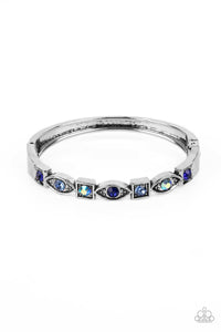 A collection of square and marquise-shaped frames arc across the wrist in a stunning geometric display. Sapphire, light sapphire, and blue iridescent rhinestones are pressed into the centers of the thick silver frames, adding irresistible sparkle to the bangle-inspired design. Features a hinged closure. Due to its prismatic palette, color may vary.