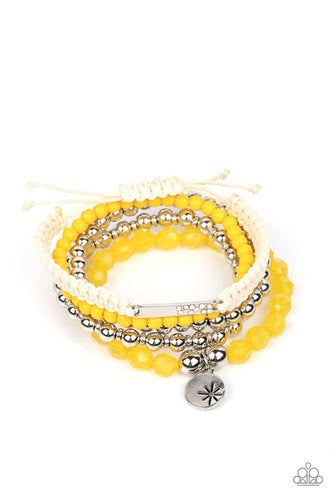 Strands of yellow beads in the vibrant Pantone® of Samoan Sun are threaded along stretchy elastic bands to create a stack of bracelets. The varying opacities of each yellow bead adds depth to the design, as a strand of silver beads adds metallic sheen. A silver disc stamped with a star offers a whimsical accent, as a silver bar dotted with opalescent rhinestones is tied to another bracelet created with ivory cording and a sliding knot closure.