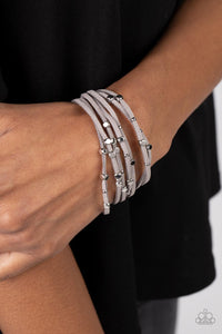 Row after row of gray suede cords layer around the wrist. Varying sizes of shiny silver studs coalesce across the cords in an out-of-this-world pattern for a starry statement. Features a magnetic closure.  Sold as one individual bracelet