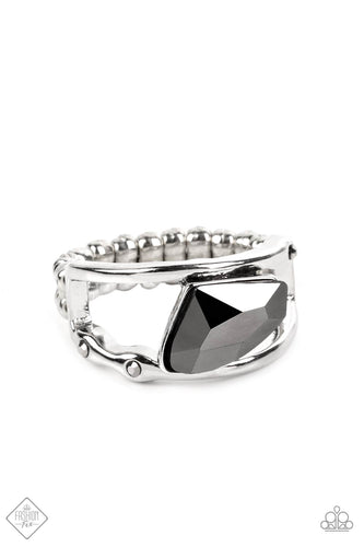 An asymmetrical, jagged piece of hematite emerges from between two bands of silver, creating a smoldering statement piece atop the finger. Tiny flecks of hematite are embedded in the silver bands, adding a hint of additional sparkle to the piece. Features a dainty stretchy band for a flexible fit.  Sold as one individual ring.