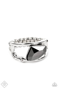 An asymmetrical, jagged piece of hematite emerges from between two bands of silver, creating a smoldering statement piece atop the finger. Tiny flecks of hematite are embedded in the silver bands, adding a hint of additional sparkle to the piece. Features a dainty stretchy band for a flexible fit.  Sold as one individual ring.