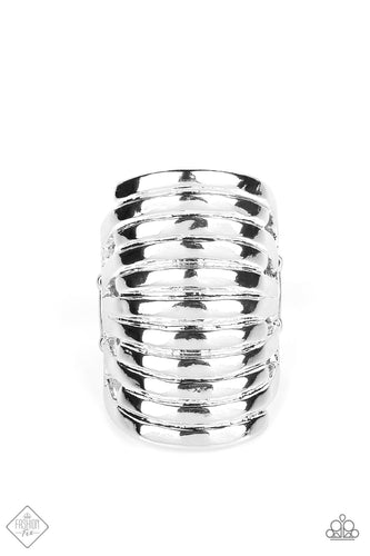 An elongated silver frame is lined with rippling texture, creating the illusion of multiple silver bands stacking up the finger. The high sheen finish creates stunning contrast to the textured surface, resulting in a deceptively simple statement piece. Features a stretchy band for a flexible fit.  Sold as one individual ring.