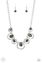 Load image into Gallery viewer, Marbled black stones are encased in classic silver frames and attached to the inside edges of warped silver hoops. The haphazard placement of the stones and the irregular shape of the silver rings add a handcrafted touch to the design, as the asymmetrical frames fall along the collar at the end of a thick silver chain. Features an adjustable clasp closure. As the stone elements in this piece are natural, some color variation is normal.
