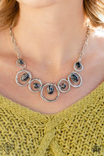 Load image into Gallery viewer, Marbled black stones are encased in classic silver frames and attached to the inside edges of warped silver hoops. The haphazard placement of the stones and the irregular shape of the silver rings add a handcrafted touch to the design, as the asymmetrical frames fall along the collar at the end of a thick silver chain. Features an adjustable clasp closure. As the stone elements in this piece are natural, some color variation is normal.
