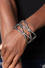 Load image into Gallery viewer, High-sheen gunmetal bars airily weaves around the wrist in a zig-zag manner into a refined statement. Featured on the crossed ribbons of the gunmetal, rows of dainty white rhinestones cluster across the display, meeting at duos of white gems in the center, for a subtle shimmer. Features a hinged closure.
