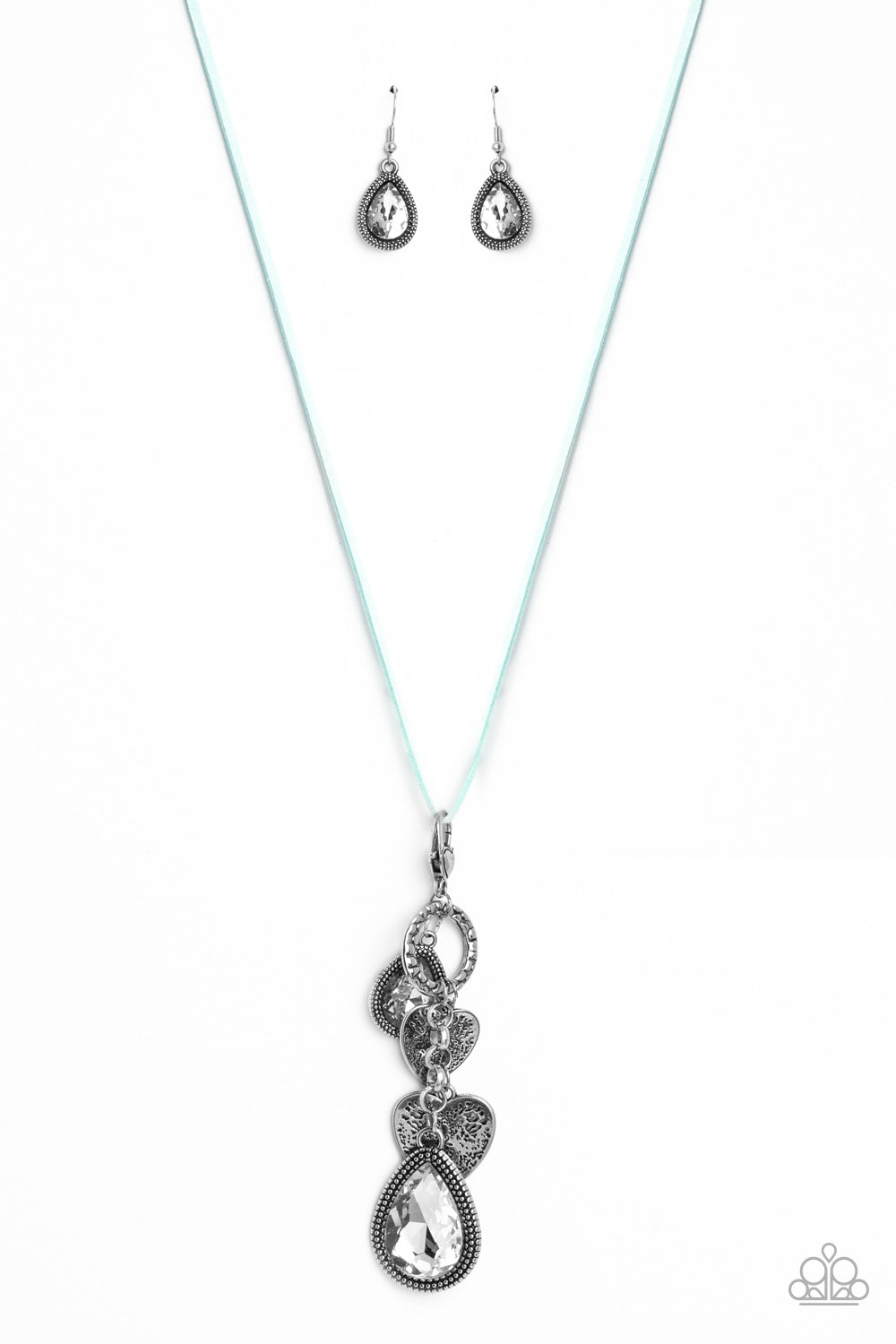 Dangling from the bottom of an elongated aqua suede string, a lobster clasp closure holds an eclectic collection of shimmer and shine. Featured on the lobster clasp, varying sizes of white teardrop gems pressed into silver studded frames, varying sizes of silver hearts brushed in an antiqued pattern, and a ring brushed in a cobblestone-like pattern create a whimsical refinement down the neckline. Features an adjustable clasp closure.