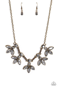 Featuring smoldering marquise style cuts, oversized smoky gems fan out from an interconnected, circular smoky rhinestone display. Separating the dauntless florals, airy brass ovals, stamped with a dot motif, create additional eye-catching sheen. Features an adjustable clasp closure.