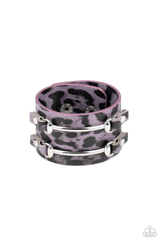 Two arcing silver bars are studded in place across the front of a thick leather band painted in purple and black cheetah print for a wild look. Features an adjustable snap closure.  Sold as one individual bracelet.