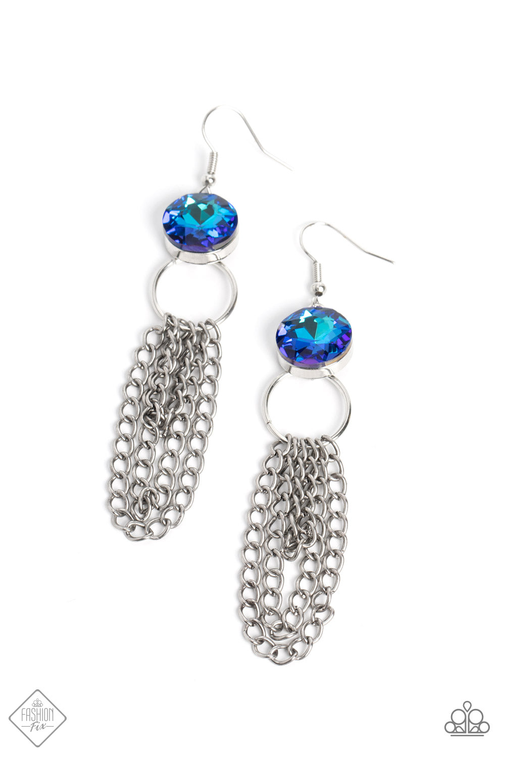 A silver ring is affixed to the back of a prominent blue gem, creating an unexpected anchoring point for strands of silver chain to drape boldly. The faceted surface of the blue gem scatters light in every direction, offering a glitzy contrast to the industrial chains that swing below. Earring attaches to a standard fishhook fitting.  Sold as one pair of earrings.