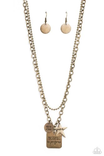 Featuring three inspirational pendants, a brass star, circle, and square fall along a brass chain. The star features the phrase 