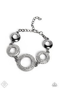 A pair of high-sheen gunmetal hoops flank a trio of larger gunmetal hoops covered in white rhinestones. Each ring features beveled surfaces, which amplify the dramatic sparkle and sheen they radiate. Features an adjustable clasp closure.  Sold as one individual bracelet.