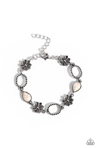 Metallic daisy charms, silver hoops studded with a dot motif, and white teardrop stones, pressed into textured silver frames interlock together around the wrist for a free-spirited flair. Features an adjustable clasp closure. As the stone elements in this piece are natural, some color variation is normal.