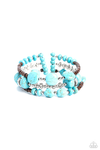 An earthy collection of brown wooden beads, classic silver beads and accents, and turquoise stones in varying sizes are threaded along invisible wires to create three bands that arc across the wrist. The bands attach to silver bars at each end, creating a whimsical illusion of three separate bracelets. As the stone elements in this piece are natural, some color variation is normal. 