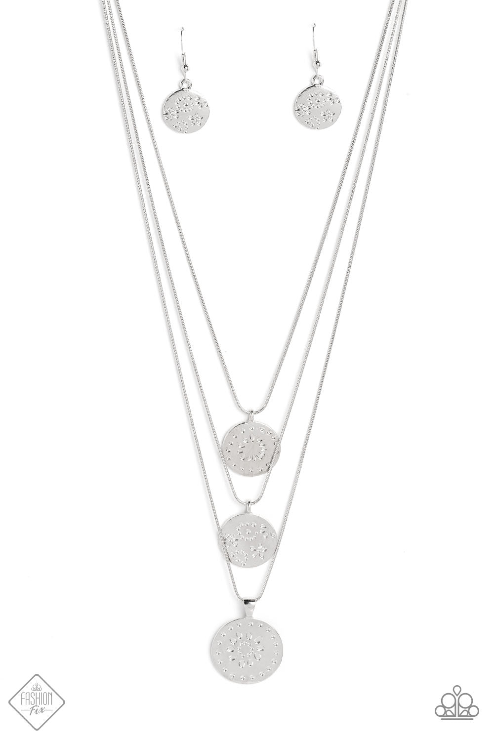 Three silver discs trickle from the bottom of three silver snake chains, creating shimmery monochromatic layers down the chest. An intricate floral design is stamped onto each disc, adding a whimsical touch to the charming design. Features an adjustable clasp closure.  Sold as one individual necklace. Includes one pair of matching earrings.