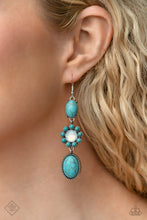 Load image into Gallery viewer, A trio of earthy turquoise stones is linked together as they fall from the ear. An oval-cut turquoise stone with a pronged silver frame anchors the cascade, followed by a round-cut opalescent bead bordered in turquoise beads. Another oval-cut turquoise stone in a studded frame finishes off the design, swaying effortlessly from the ear in a whimsical finish. Earring attaches to a standard fishhook fitting. As the stone elements in this piece are natural, some color variation is normal.
